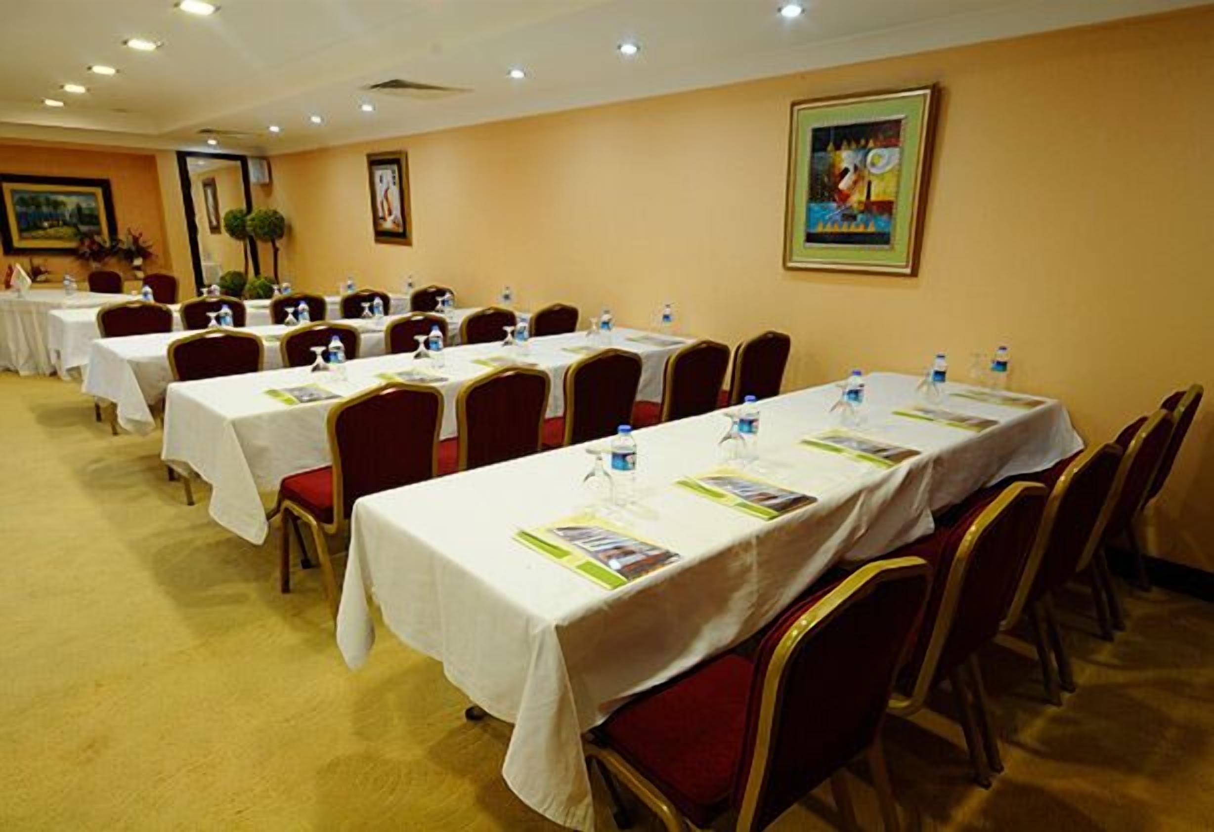 Un salón de conferencias con varias mesas, cada una con botellas de agua y folletos.