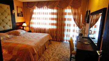 A hotel room with a large bed, a desk, and a chair.