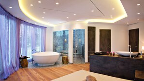 Un baño moderno con una bañera independiente, un espejo grande y un tocador con lavabo.