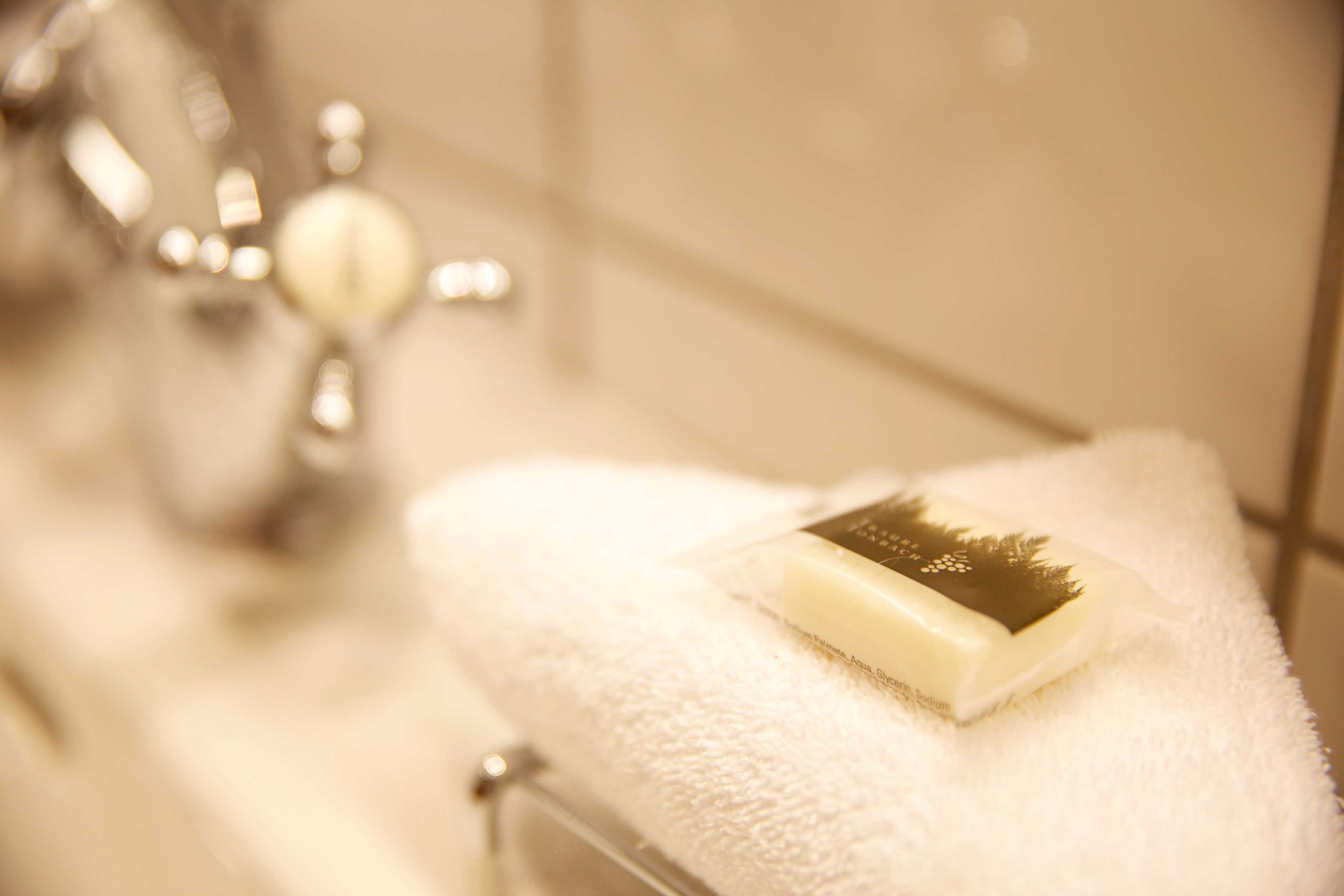 A bathroom with a white towel and a bar of soap on a sink.