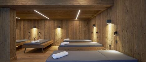Una habitación de madera con cuatro camillas de masaje, cada una con una toalla.