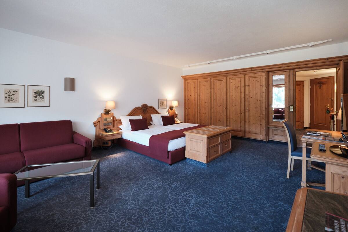 Ein Hotelzimmer mit Bett, Schreibtisch, Stuhl, Sofa und Kleiderschrank.