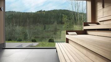 Una habitación moderna con un amplio ventanal que ofrece vistas a un paisaje montañoso cubierto de bosque.