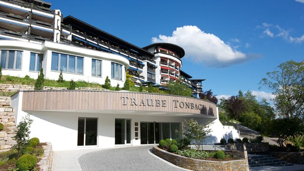 A modern hotel with a prominent sign reading "TRAUFE TONBACH".