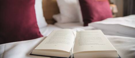 Un libro abierto sobre una cama con almohadas blancas y rojas.