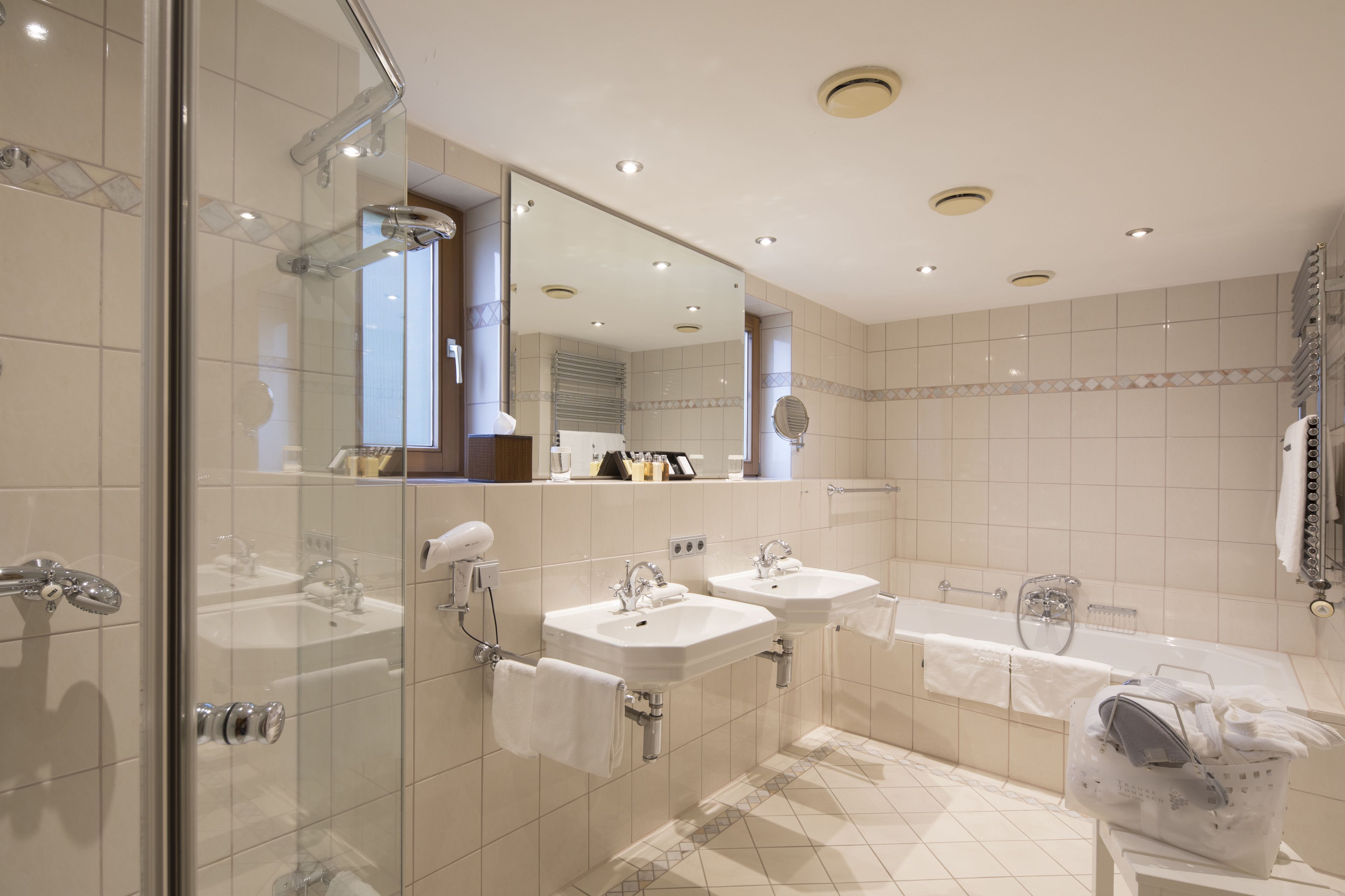 Un baño moderno con dos lavabos, una bañera y una cabina de ducha con mampara de vidrio.