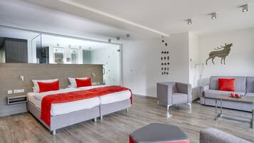 Une chambre d’hôtel moderne, dotée d’un grand lit, d’un canapé, d’un fauteuil, d’une petite table et d’un miroir fixé au mur.