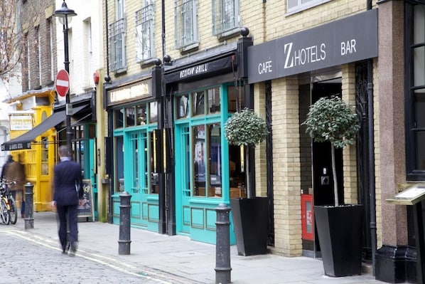 A building with a cafe and a bar on the ground floor, a restaurant above, and a yellow taxi outside. - The Z Hotel Soho (London)