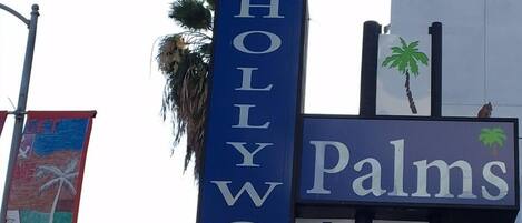 Une enseigne d’hôtel indiquant « Palms Inn & Suites » et l’adresse « 6055 Hollywood ».