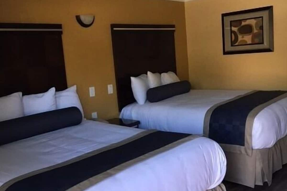 A hotel room with two beds, a mural on the ceiling, and a framed picture on the wall.
