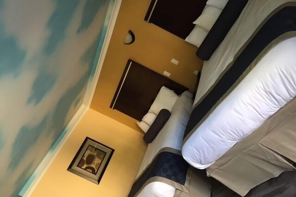 A room with bunk beds, a framed picture on the wall, and a window with a view of the sky.