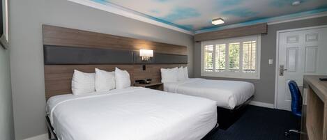 A hotel room with two beds, a desk, a chair, a window with blinds, and a ceiling painted to resemble clouds.
