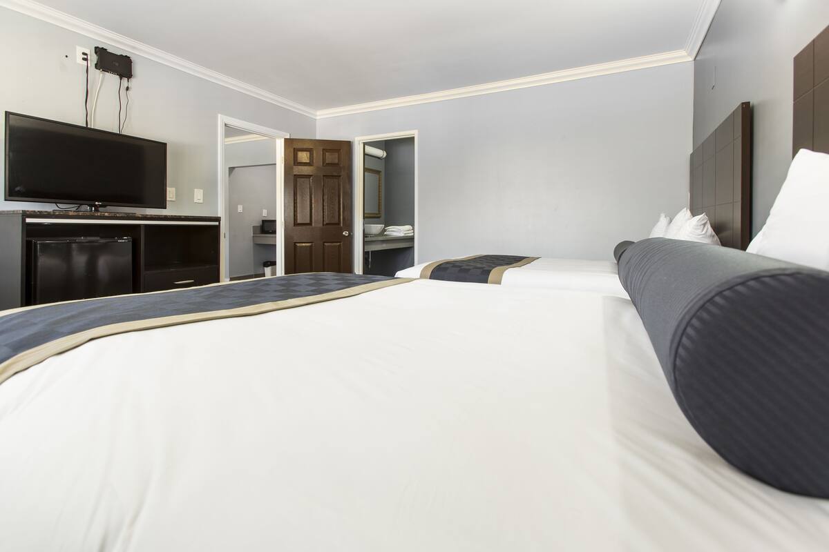 A hotel room with a large bed, a television, and a wardrobe.