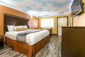 A hotel room with a bed, a desk, a TV, and a door. - Hollywood Palms Inn and Suites (Los Angeles)
