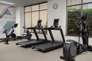 Un gimnasio con cintas de correr, elípticas y bicicletas estáticas.
