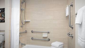 A modern bathroom with a bathtub, grab bars, and a showerhead.