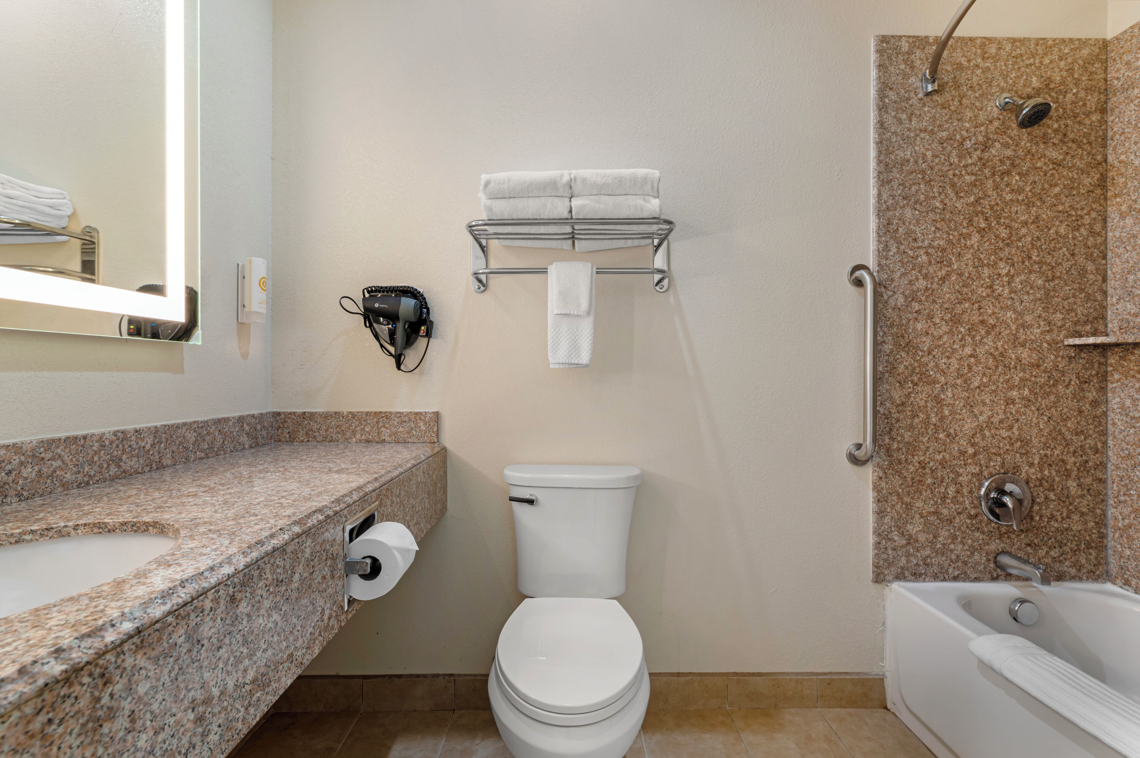 Un baño con inodoro, lavamanos, toallero y zona de ducha.