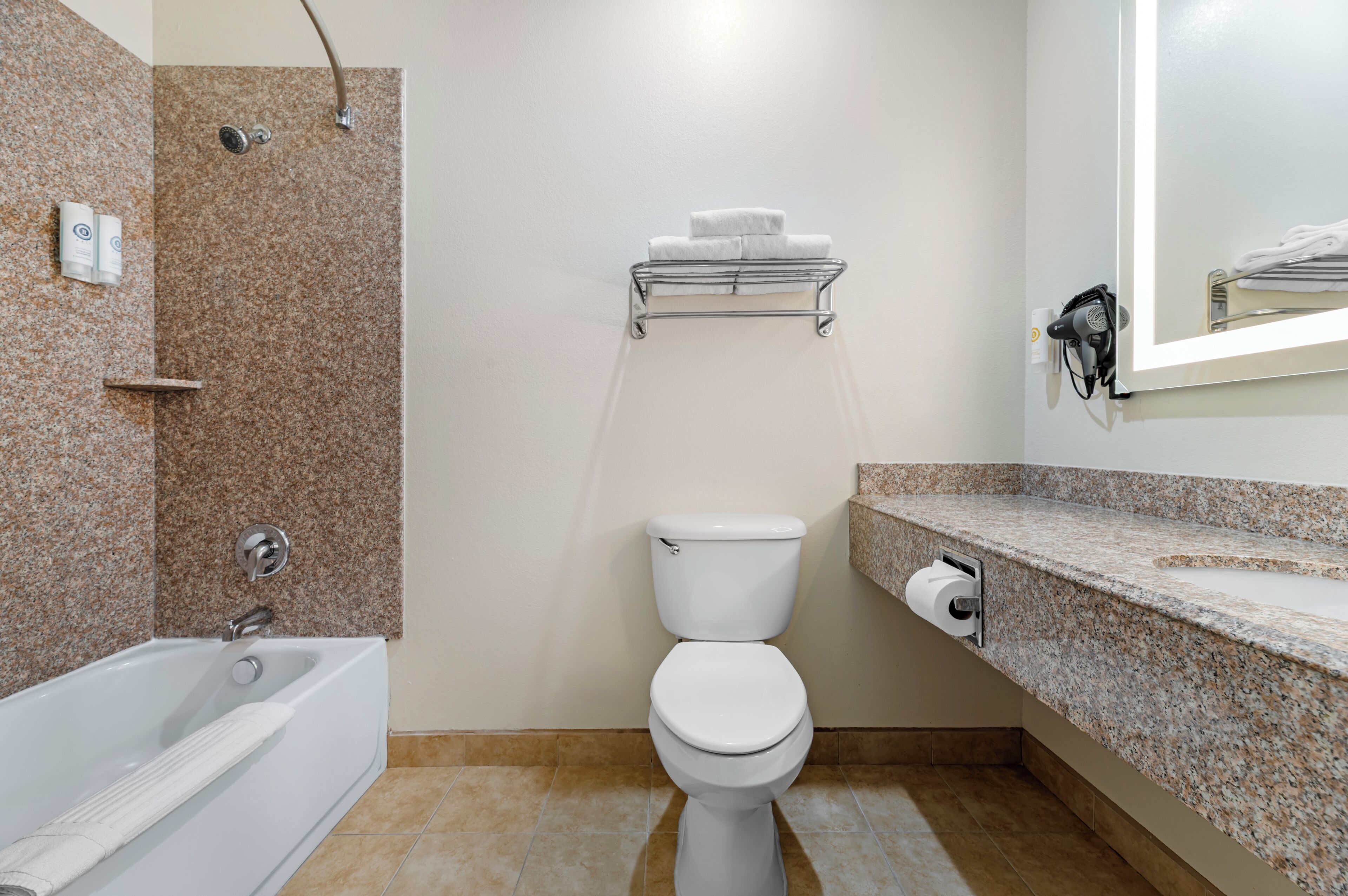 A bathroom with a bathtub, toilet, shower, and a towel rack.