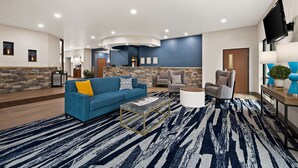 A spacious living area with a blue sofa, a coffee table, and a stone accent wall. - Comfort Suites Hudson I-94 (Hudson)