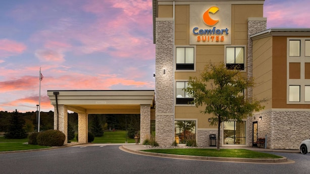 A Comfort Suites hotel with a stone facade, multiple windows, and a covered entrance. - Comfort Suites Hudson I-94 (Hudson)