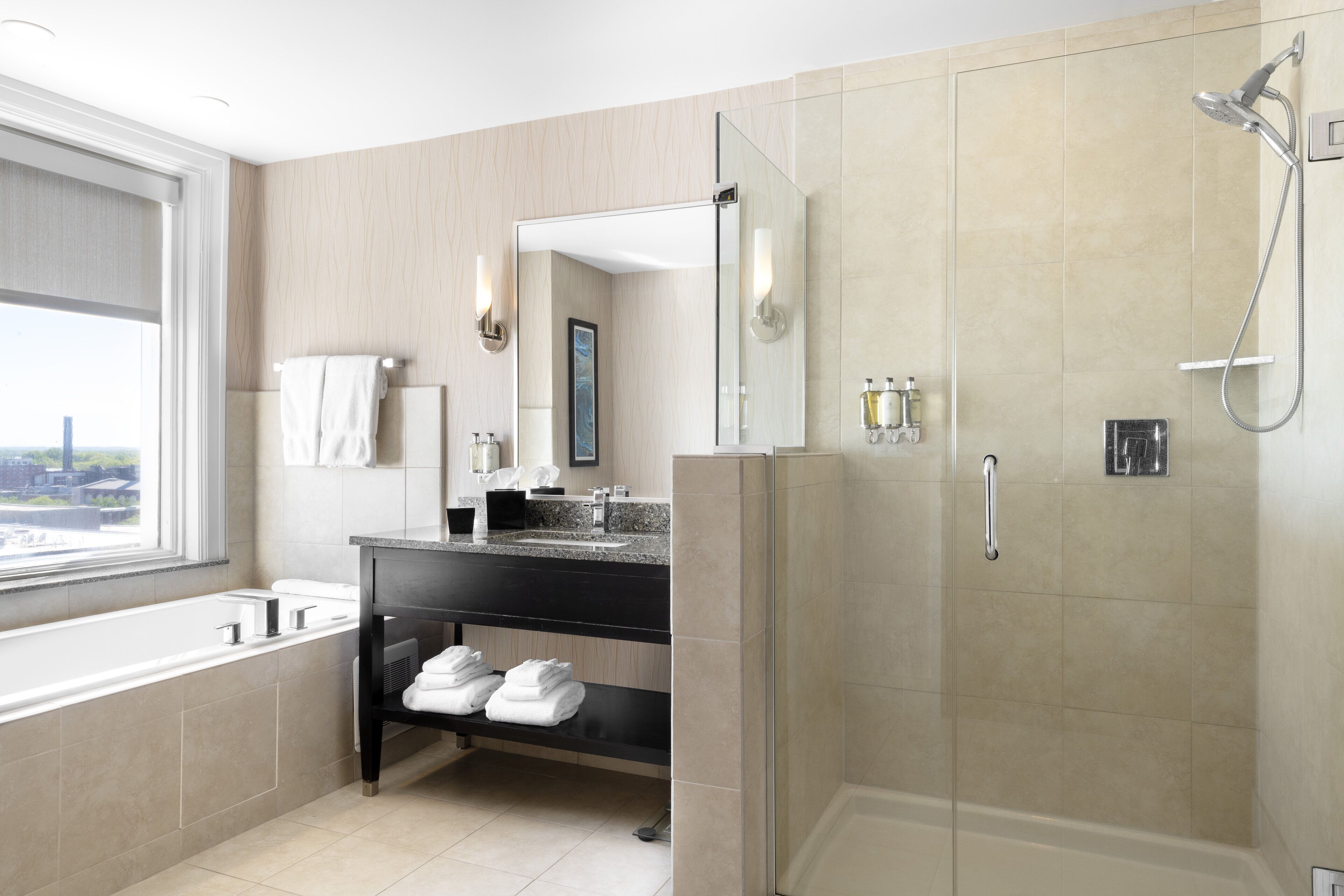 A modern bathroom with a bathtub, a shower, a vanity with a mirror, and a shelf with towels.