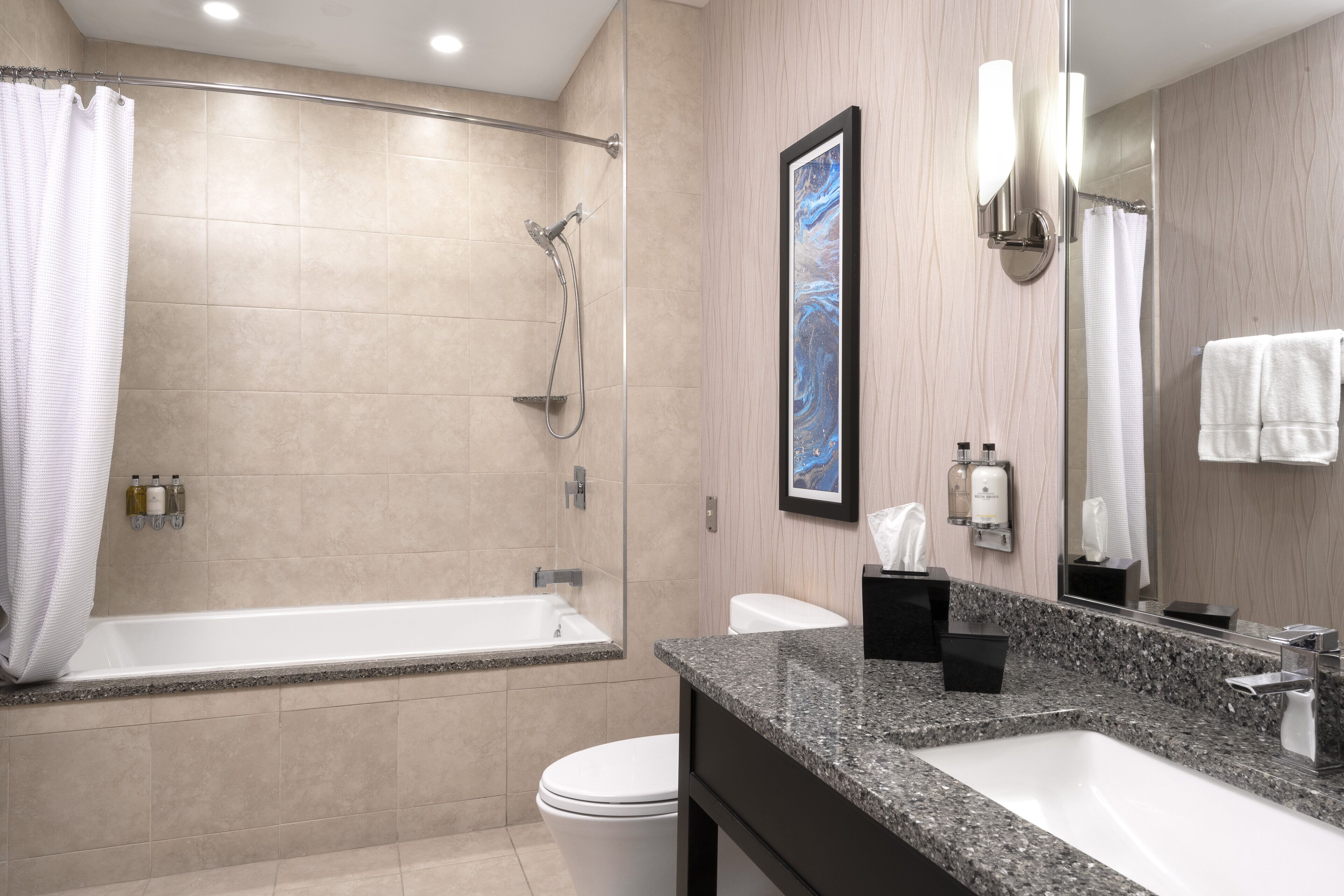 A modern bathroom with a bathtub, toilet, and sink.