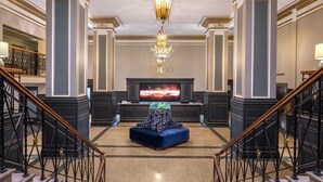 A grand lobby with a large TV screen, a chandelier, and a blue sofa.