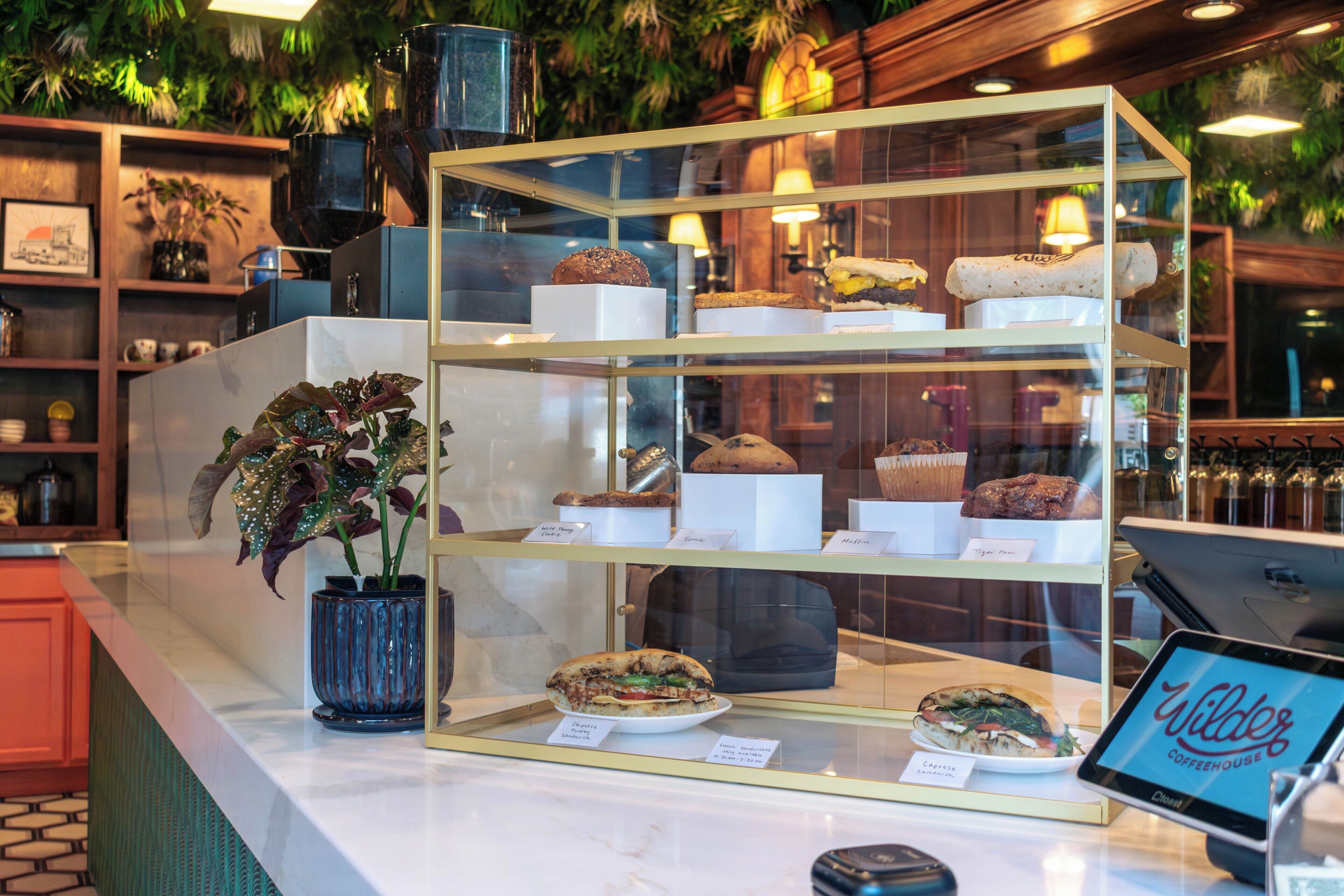 A bakery display with various baked goods and a tablet with the name "Wilder Coffeehouse".