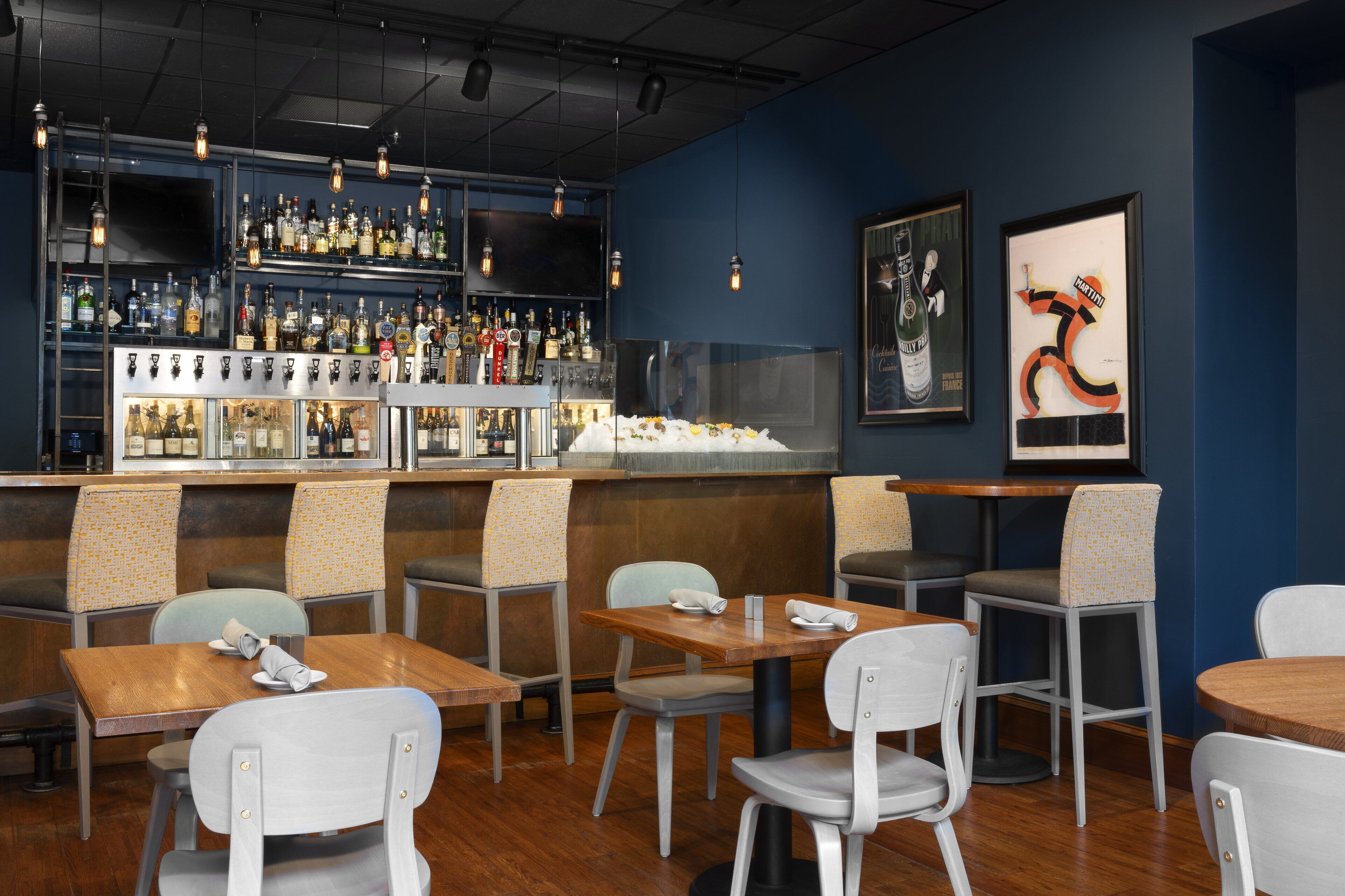 A bar area with shelves of bottles, a television, and framed artwork.