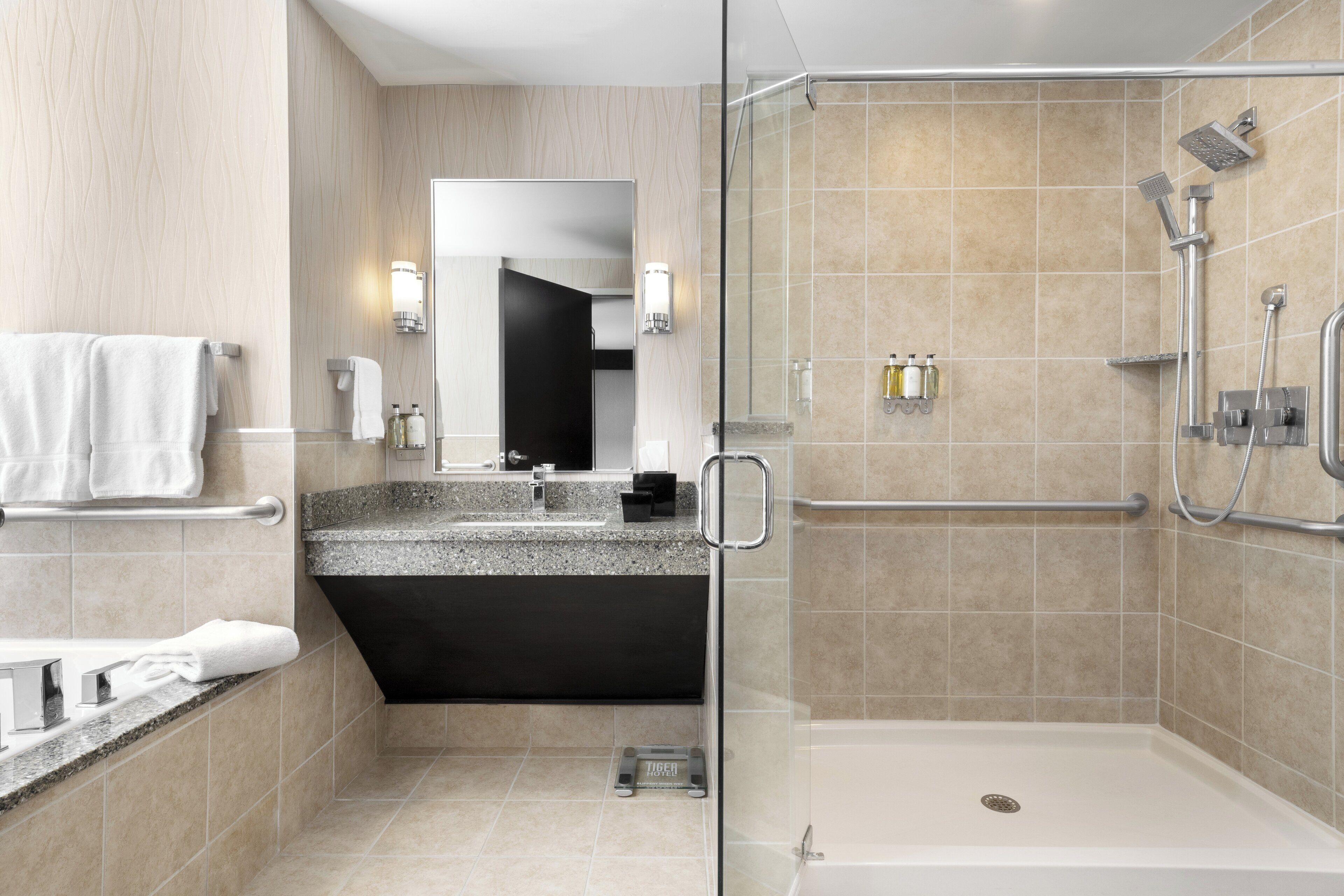 A modern bathroom with a glass-enclosed shower, a vanity with a sink, and a towel rack.