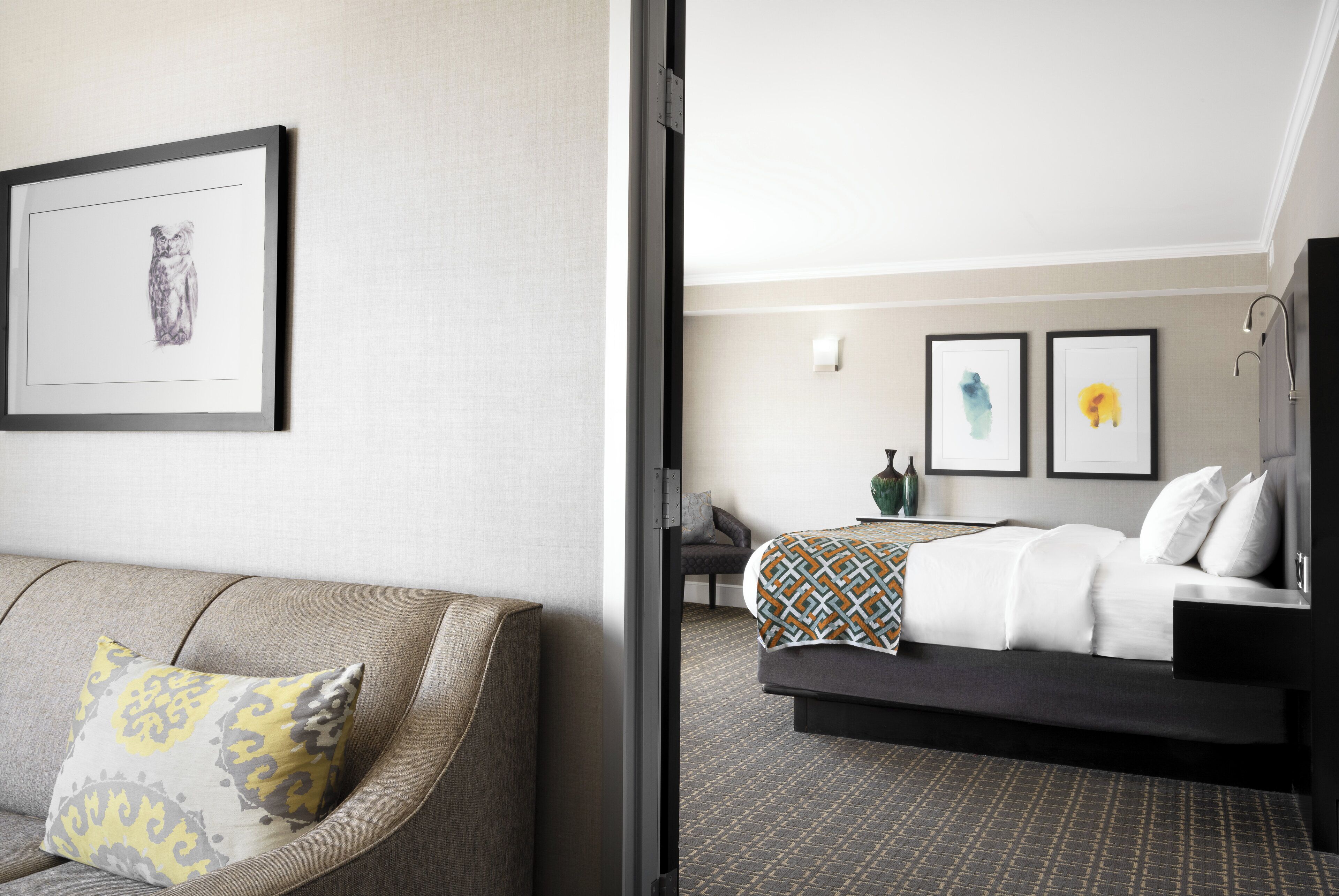 A hotel room with a bed, a sofa, and a framed picture on the wall.