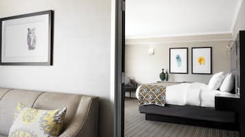 A hotel room with a bed, a sofa, and a framed picture on the wall.