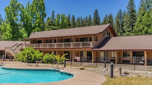 A two-story lodge with a pool, outdoor seating, and a forest backdrop. - Amador Hotel (Pioneer)