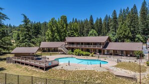 A lodge with a pool, outdoor deck, and multiple buildings surrounded by forest. - Amador Hotel (Pioneer)
