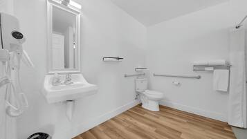 Un baño moderno con lavamanos, espejo, inodoro y ducha blancos.