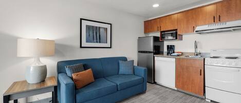 A compact kitchen with a refrigerator, microwave, stove, and wooden cabinets.