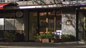 A modern building with a glass facade, outdoor seating, and a visible address number. - Carlton Lygon Lodge (Carlton)