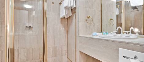 A modern bathroom with a glass-enclosed shower, a marble vanity, and a large mirror.