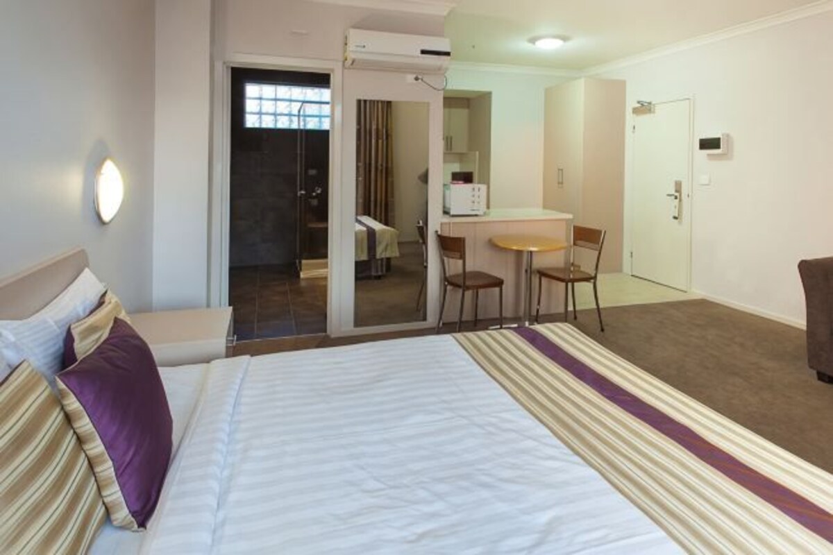 Una habitación de hotel con cama, escritorio, silla y puerta.