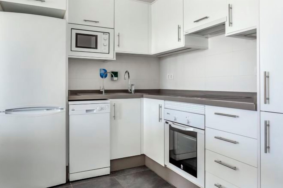 A modern kitchen with white cabinetry, a built-in microwave, a dishwasher, and an oven.