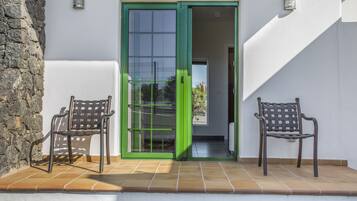 A patio with two chairs and a sliding glass door leading to an interior space.