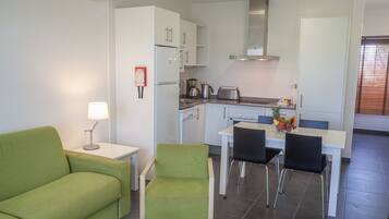 A modern kitchen with white cabinets, a stainless steel range hood, and a dining area with a table and chairs.