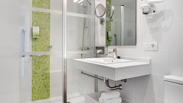 Un bany modern amb plat de dutxa de vidre, un lavabo blanc i un mirall.