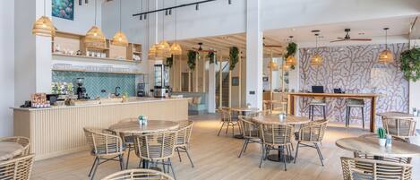 A spacious restaurant with high ceilings, exposed beams, and a variety of seating options including wicker tables and chairs.