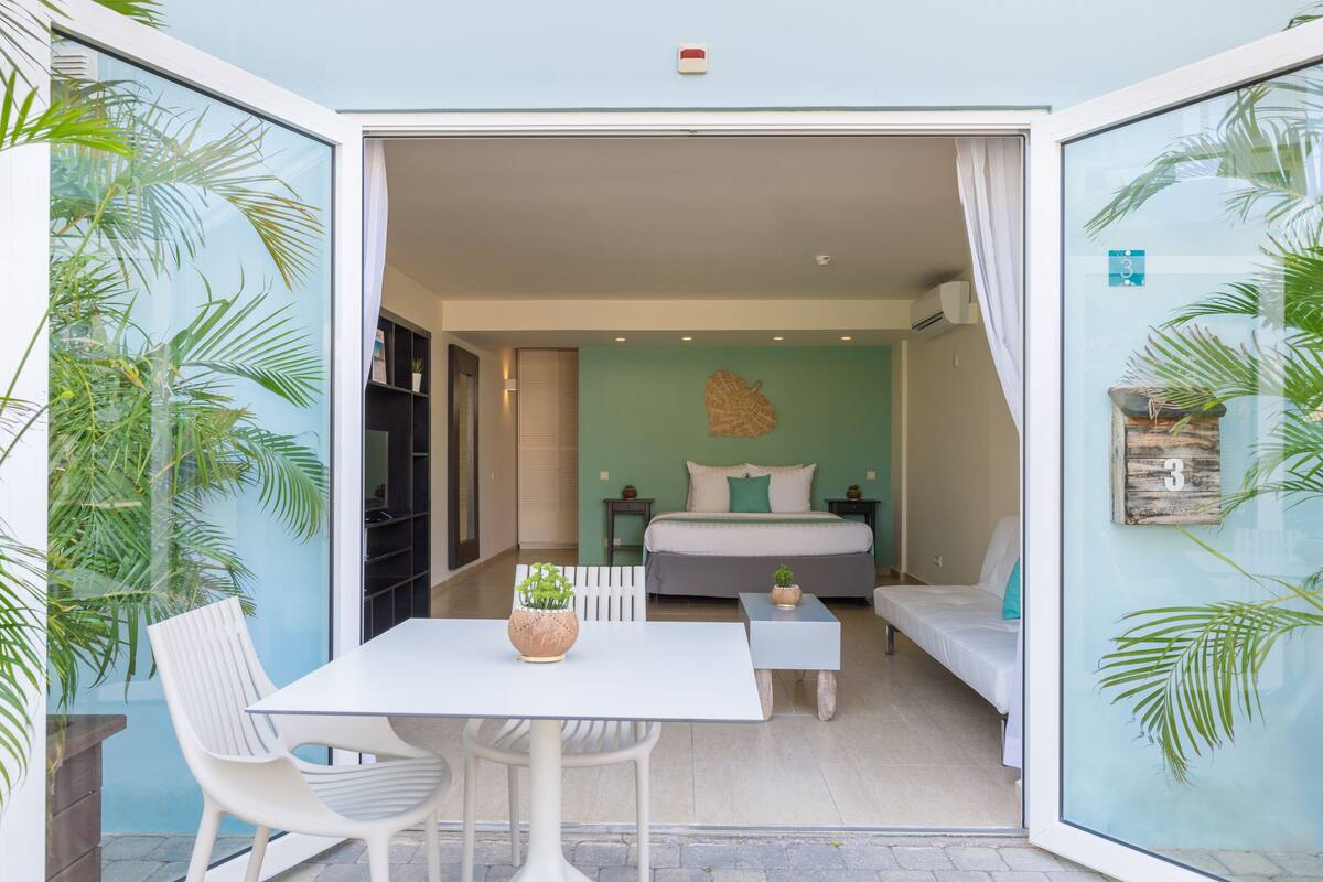 Un dormitorio pequeño con cama, mesitas de noche y una zona de estar.