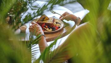 A meal with toast and fruit on a plate, surrounded by greenery.