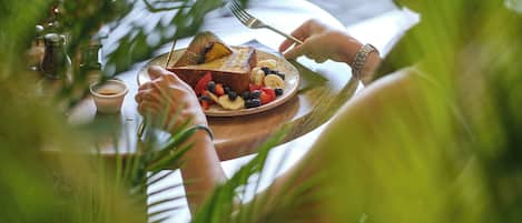 A meal with toast and fruit on a plate, surrounded by greenery.