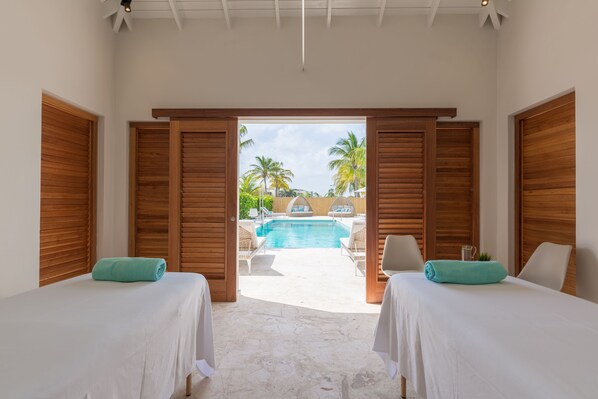 Una habitación con dos camas, vistas a una piscina y contraventanas de madera.