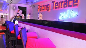 A hotel bar named 'Patong Terrace' with a neon sign, seating area with cushions, and a counter. - Patong Terrace (Patong)