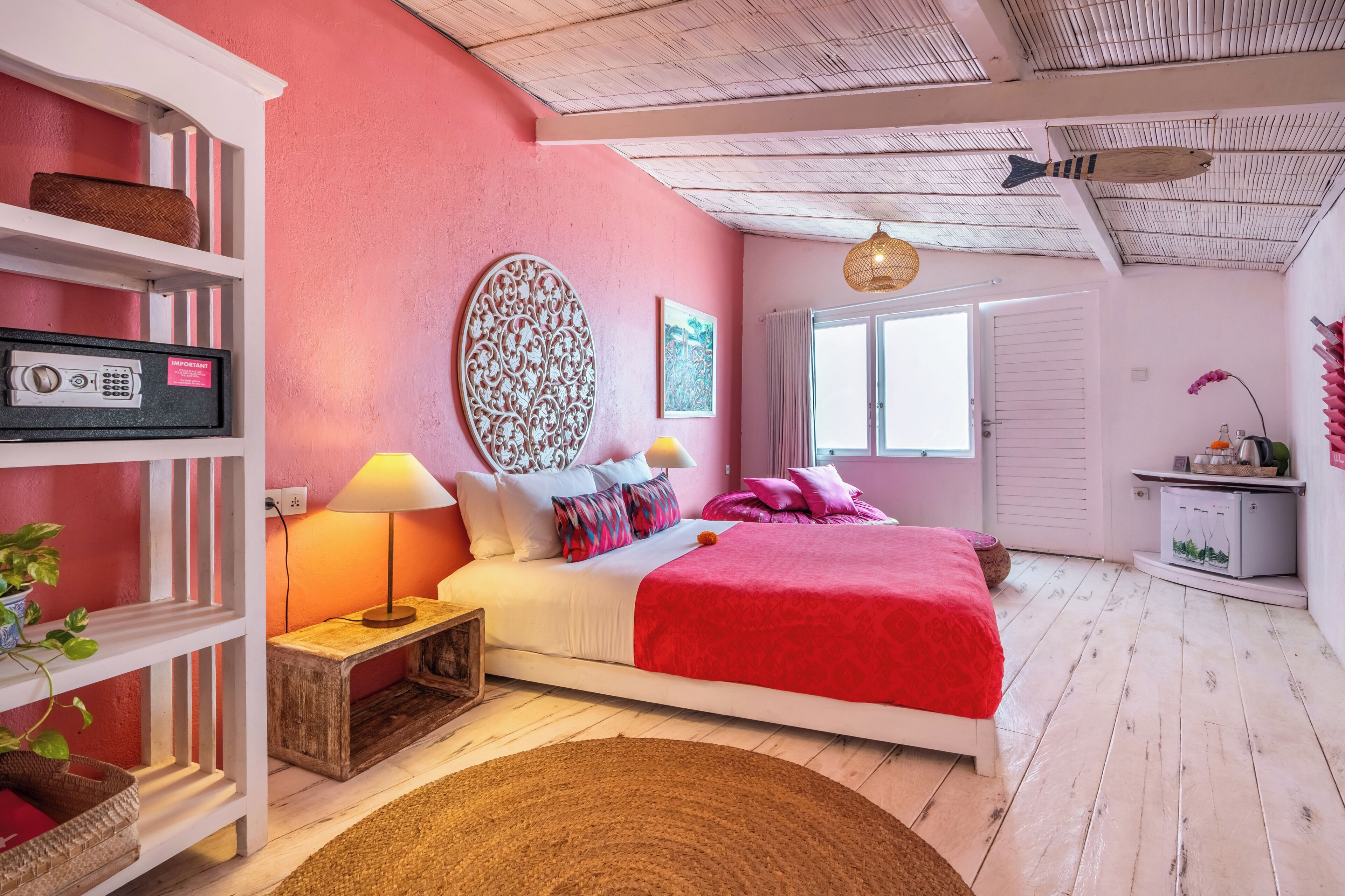 A bedroom with a bed, bedside tables, a lamp, a shelf with a basket, a wall clock, and a door.
